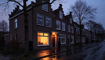 Woonstraat in de vroege avond tijdens de donkere dagen, één huis met licht aan